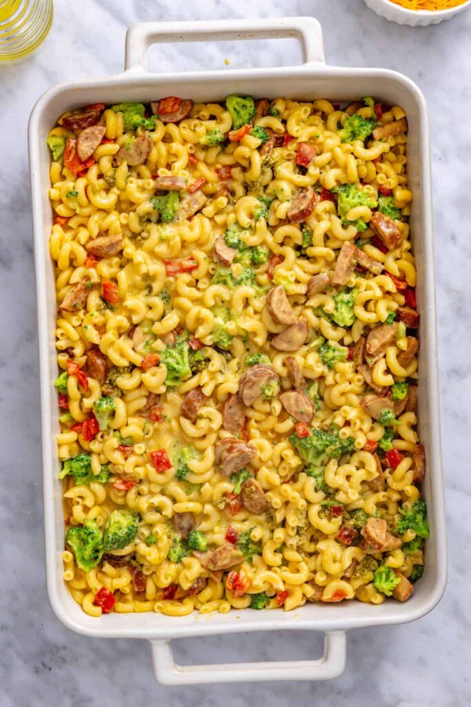 Remaining broccoli cheddar pasta spread over the pesto layer in a baking dish