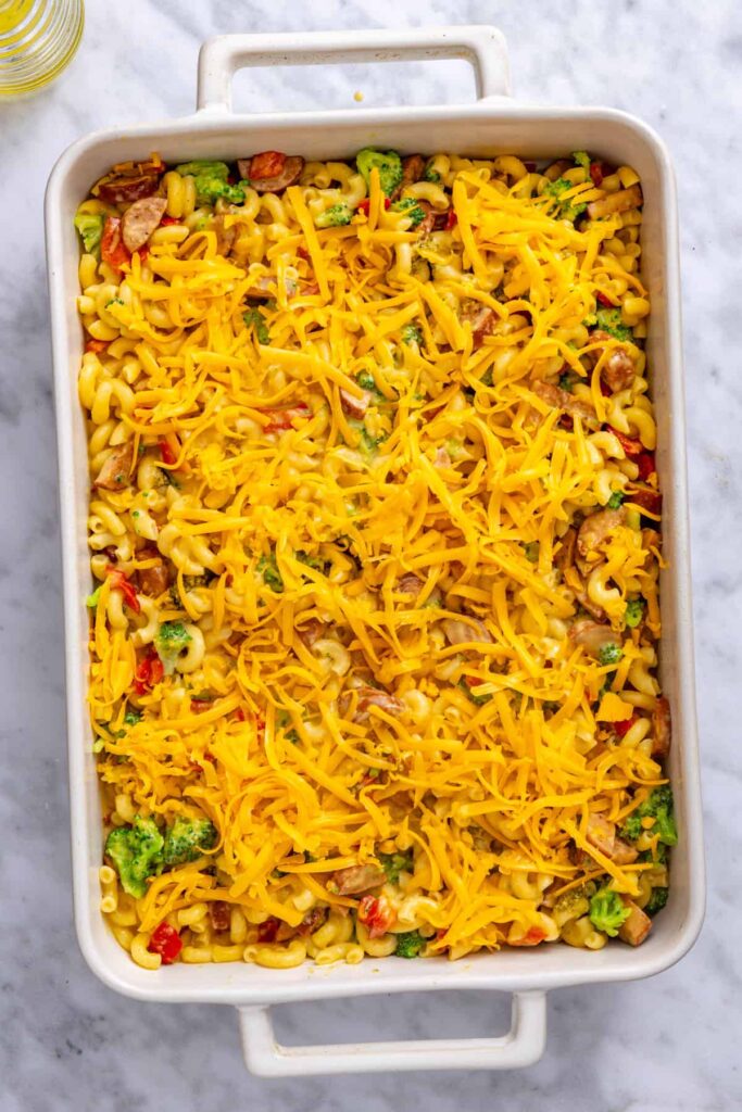 Freshly shredded cheddar cheese covering the top of the pasta before baking