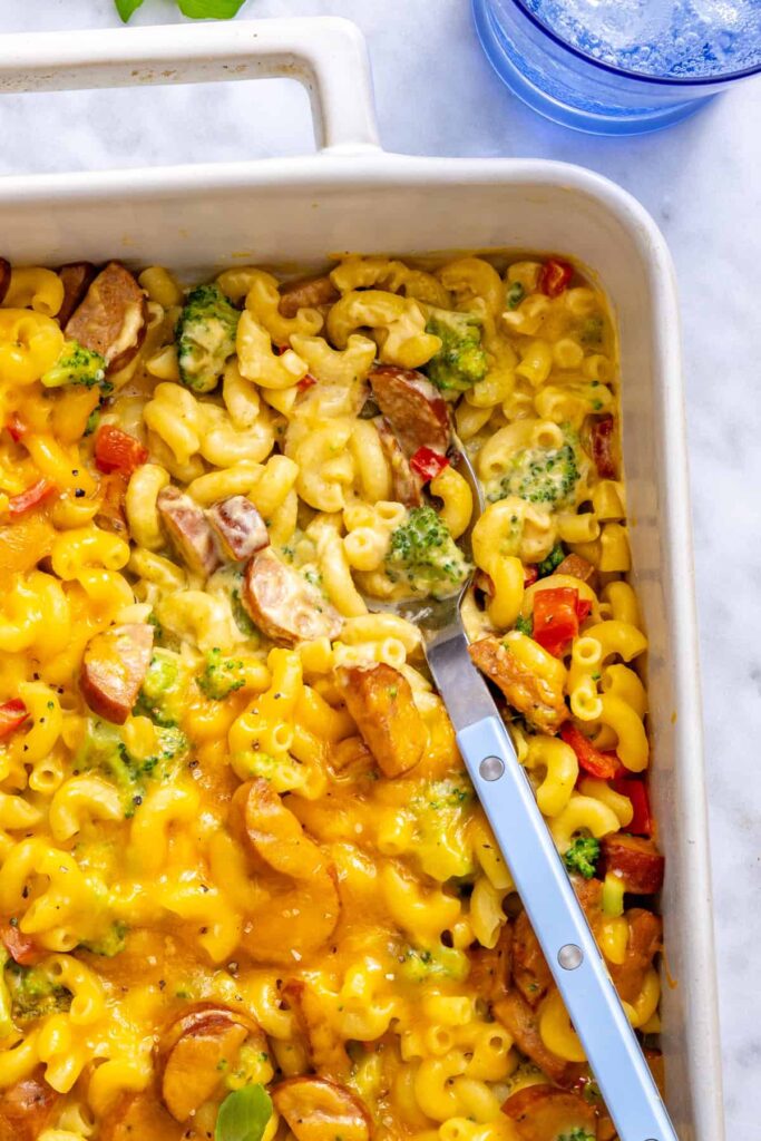 Close-up of a spoon lifting broccoli cheddar pasta from the baked casserole