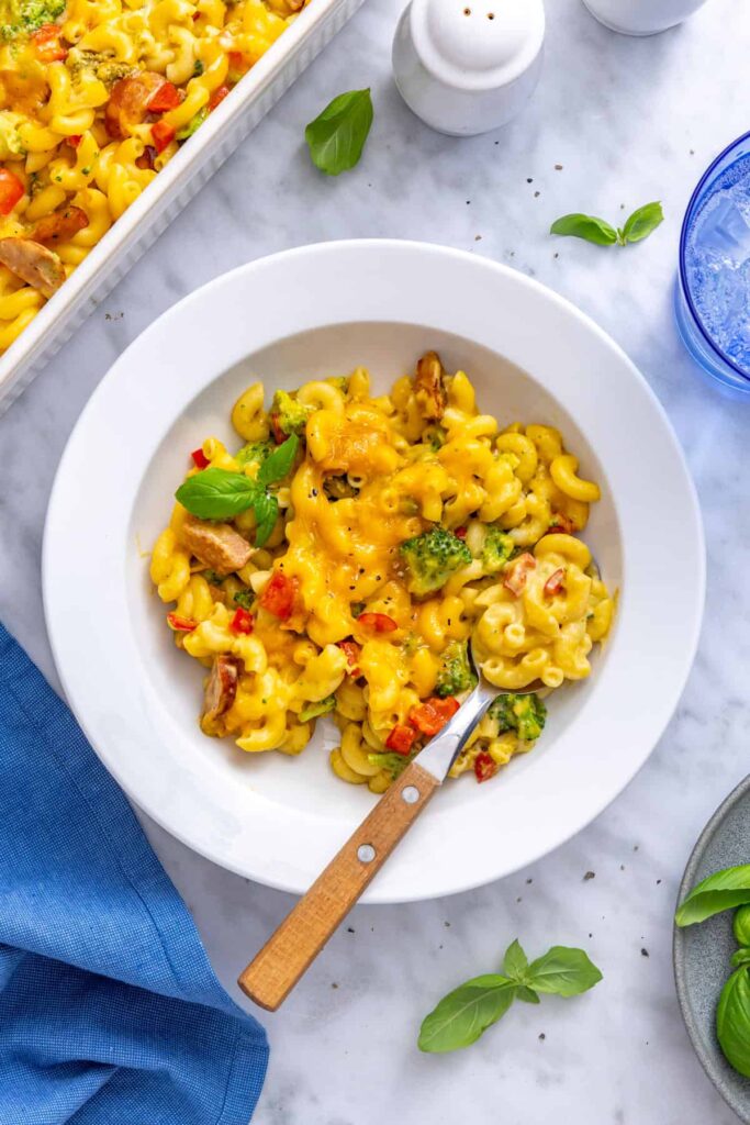 Single serving of broccoli cheddar pasta in a pasta bowl garnished with fresh basil