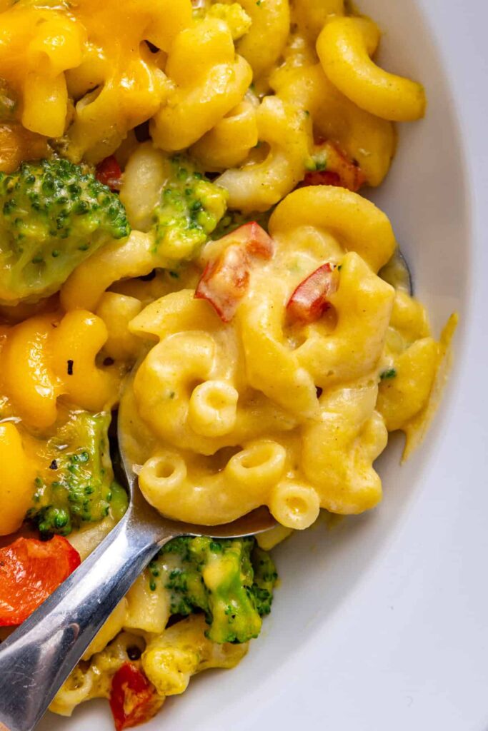 Close-up of a serving of broccoli cheddar pasta with a spoon ready to scoop