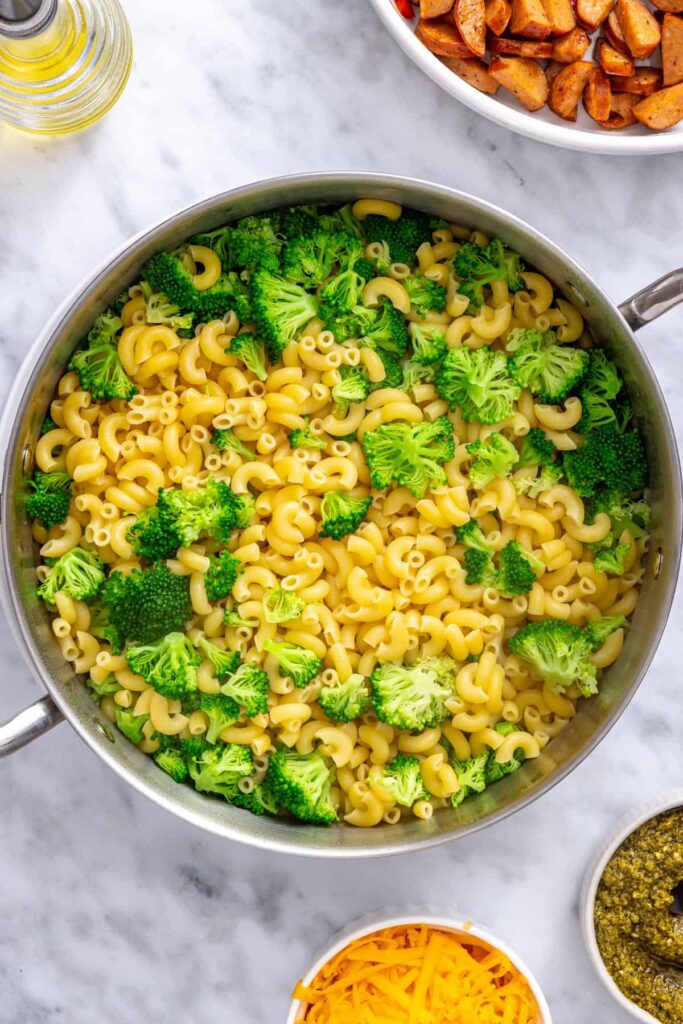 Small broccoli florets cooking with gluten-free pasta in boiling water