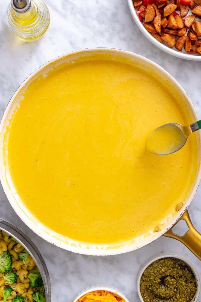 Smooth cheddar sauce cooking over low heat until thick enough to coat a spoon