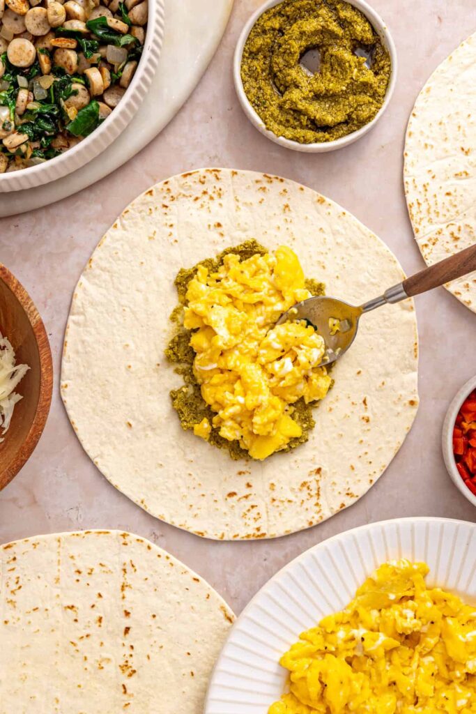 Scrambled eggs added to a tortilla for a breakfast burrito