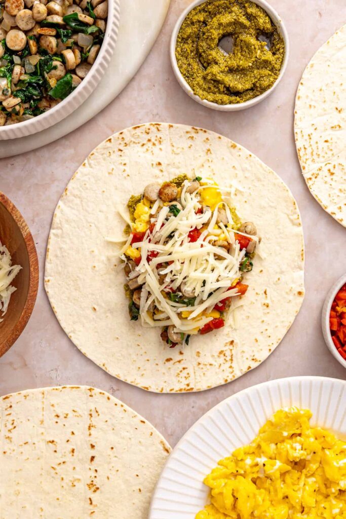 Shredded mozzarella added to the filling of a chicken pesto breakfast burrito