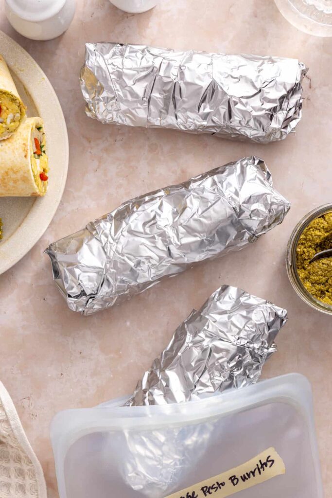 Foil-wrapped chicken pesto breakfast burritos prepared for meal prep and storage