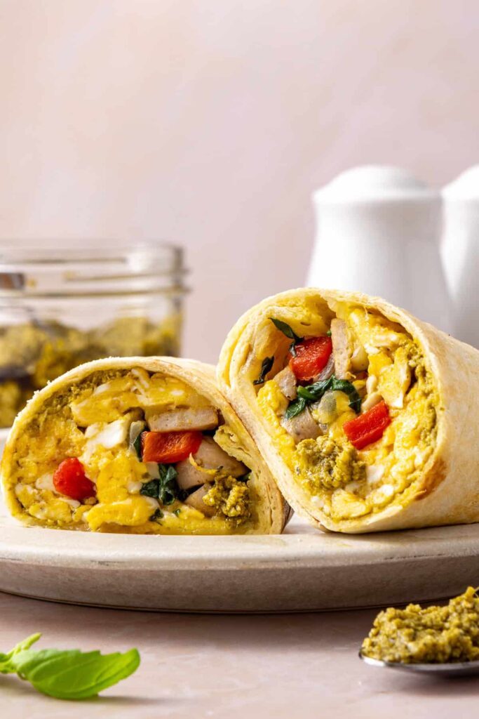 High-protein chicken breakfast burrito cut in half with eggs, chicken sausage, spinach, roasted red peppers and mozzarella