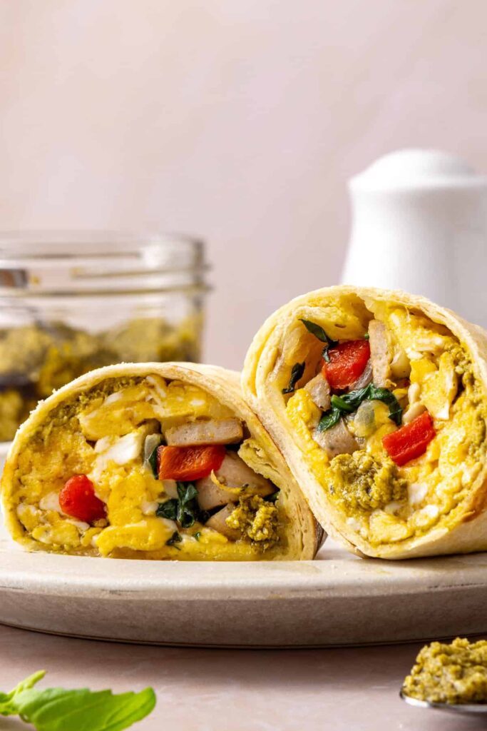 Chicken pesto breakfast burrito sliced in half and served with basil pesto