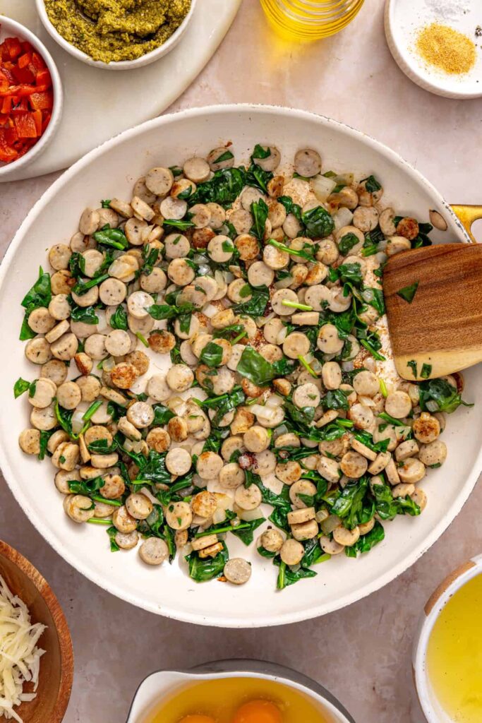 Spinach wilting with chicken sausage and onion for breakfast burritos