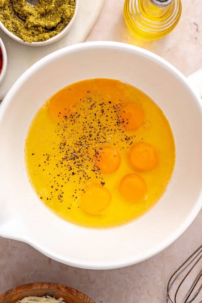 Eggs, egg whites, garlic powder, salt and pepper in a bowl, ready to be scrambled for breakfast burritos