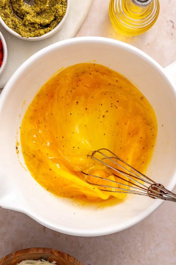 Whisking eggs and egg whites seasoned with garlic powder, salt and pepper