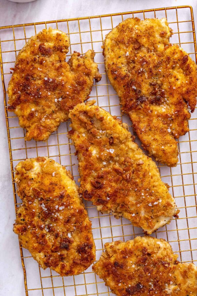Golden crispy chicken cutlets resting on a wire rack after pan-frying.