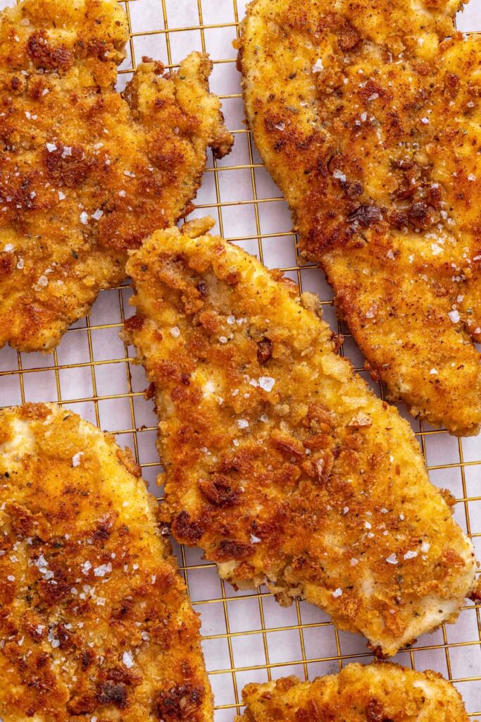 texture detail shot of crispy chicken cutlets before being sliced and added to apple arugula salad