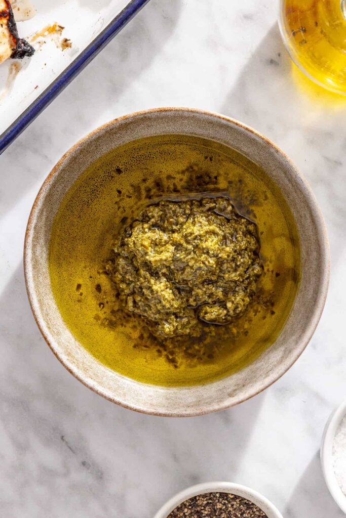 Pesto and extra-virgin olive oil ready to be whisked together for pasta salad dressing