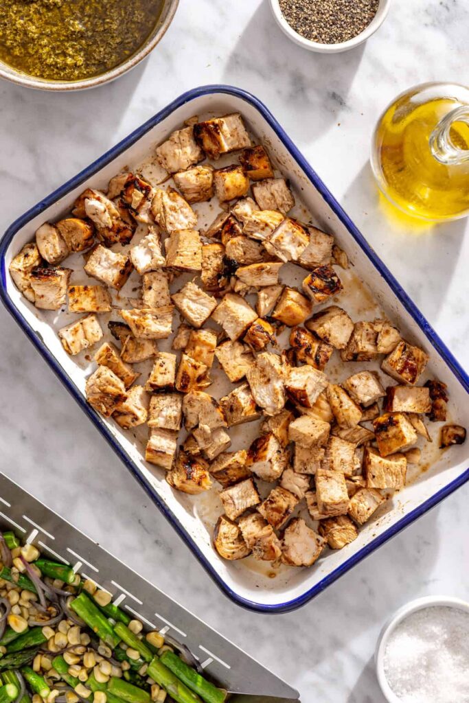 sliced grilled chicken, ready to be added to a pesto pasta salad