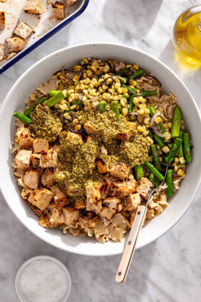 Pesto dressing poured over chicken, pasta and grilled vegetables