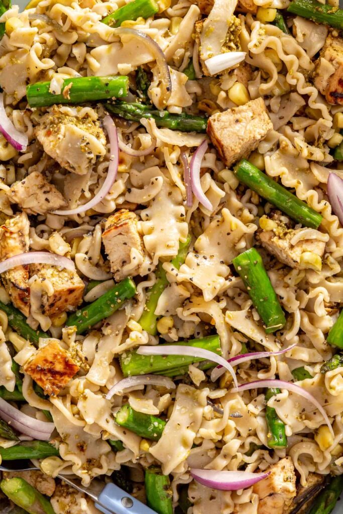 Close-up of chicken pesto pasta salad with grilled vegetables and pesto-coated pasta