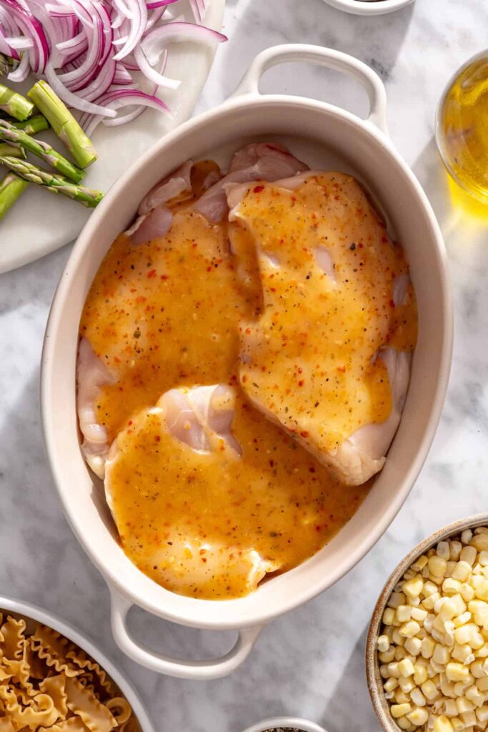 Boneless chicken marinating with Italian vinaigrette and lime juice for grilled pasta salad
