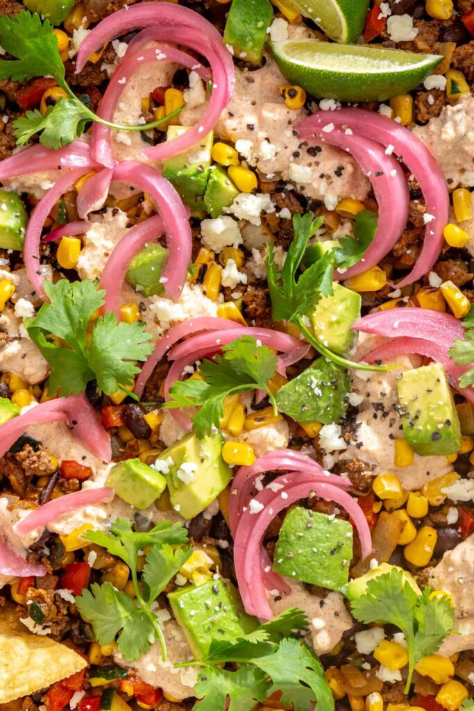 Close-up of street corn taco skillet with seasoned ground beef, black beans, fire-roasted corn, and creamy cotija sauce