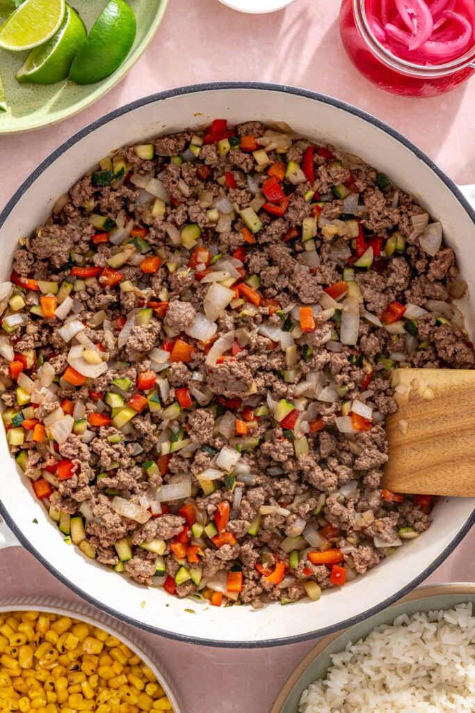 Lean ground beef cooking with onion, bell pepper, and zucchini in a skillet