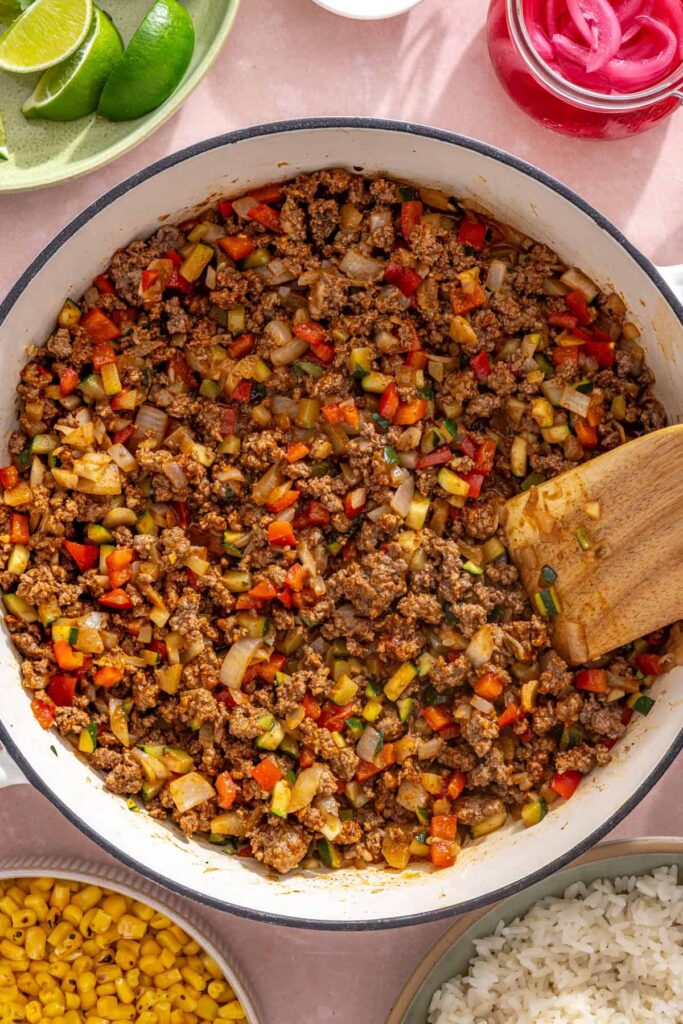 Seasoned ground beef and vegetables simmering with taco seasoning in a skillet
