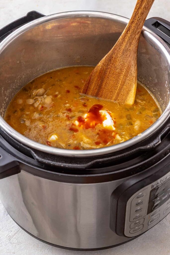 stirring the finished Instant Pot buffalo chicken chili before serving