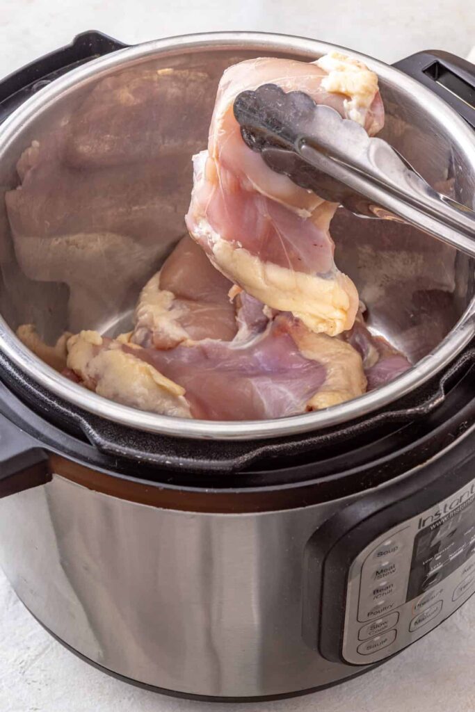 adding chicken thighs to an Instant Pot for buffalo chicken chili