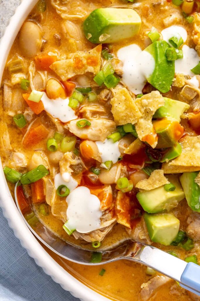 Close-up bowl of creamy buffalo chicken chili showing shredded chicken, beans and vegetables