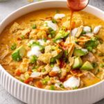 Instant Pot buffalo chicken chili topped with avocado, green onion and ranch with buffalo sauce drizzled over top