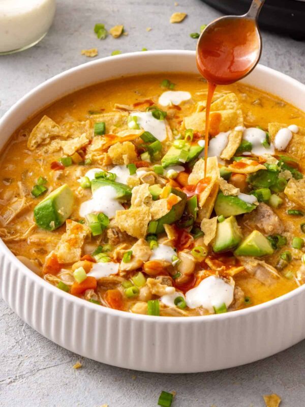 Instant Pot buffalo chicken chili topped with avocado, green onion and ranch with buffalo sauce drizzled over top