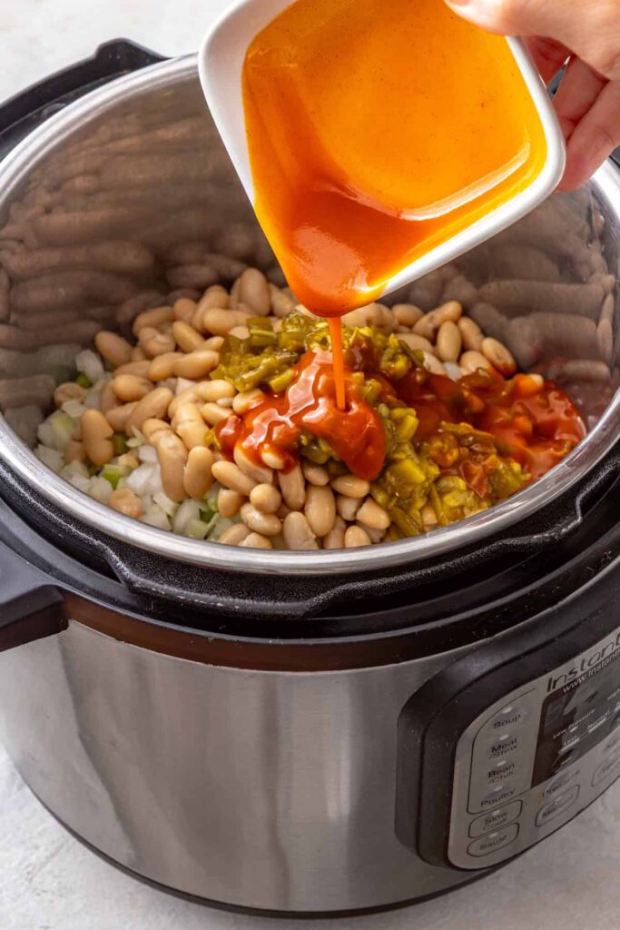 hot sauce added to an Instant Pot for a high-protein buffalo chicken chili recipe