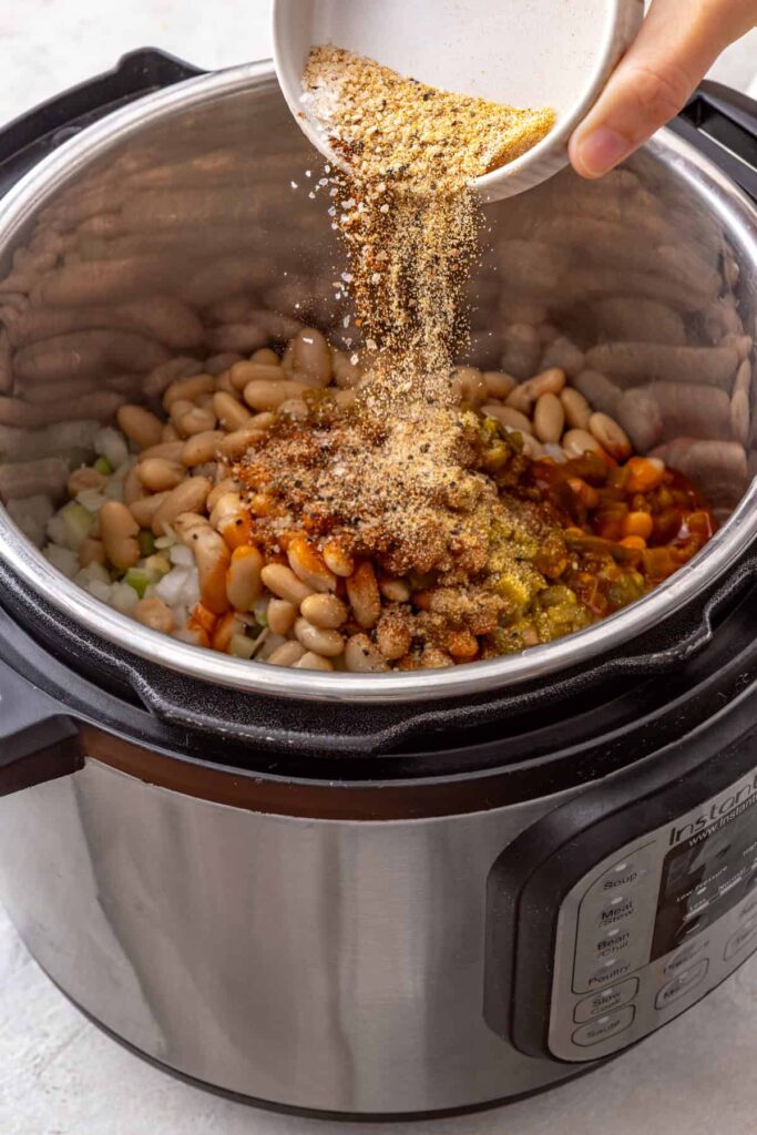 adding seasonings over top of ingredients for a buffalo chicken chili Instant Pot recipe