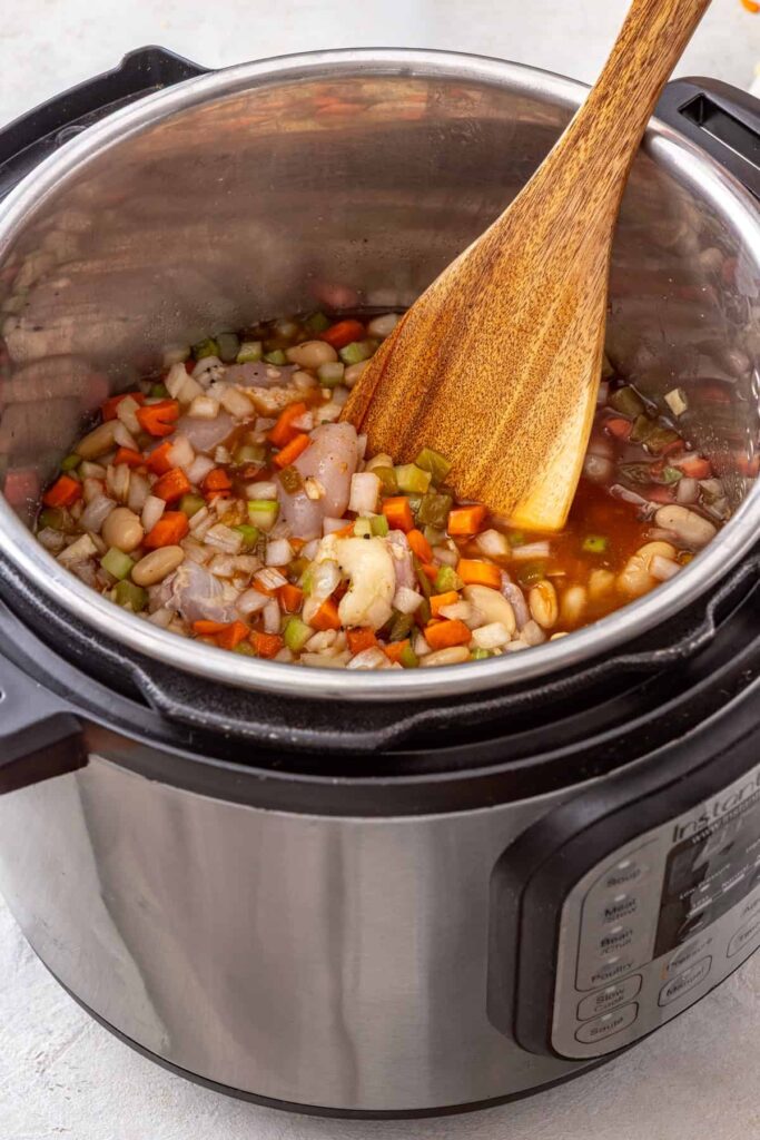 Ingredients being stirred together in the Instant Pot for buffalo chicken chili