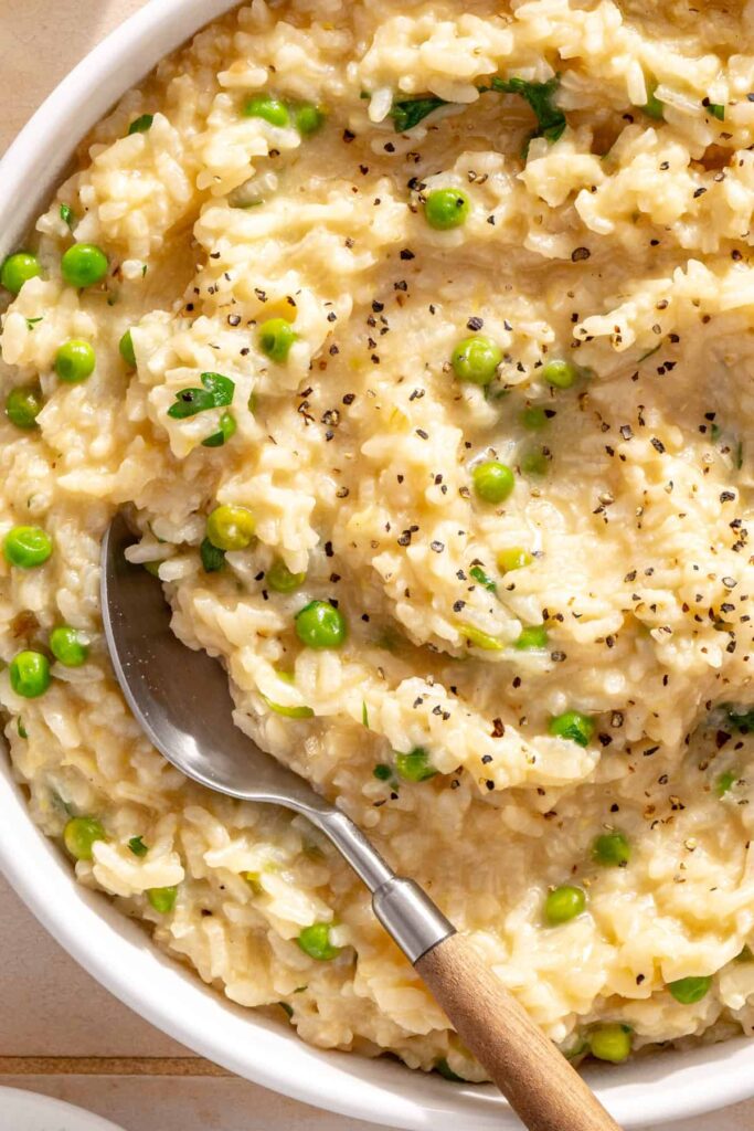 Close-up of creamy parmesan rice with fresh herbs and toasted pine nuts