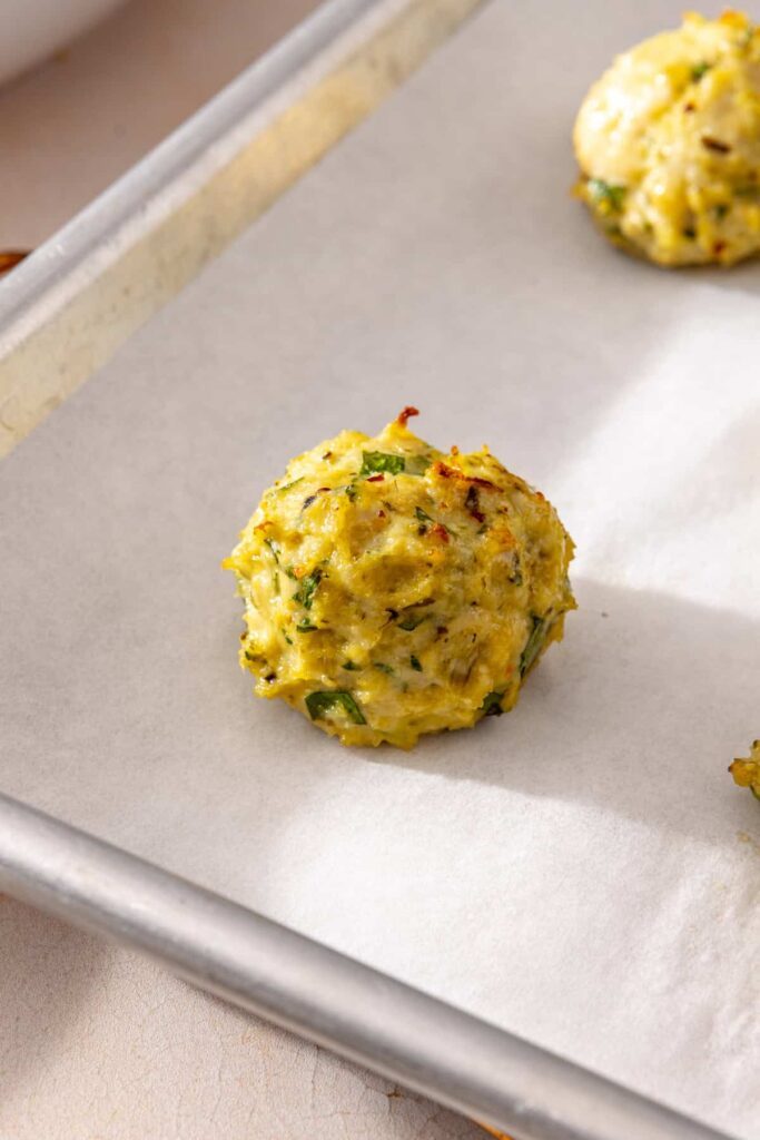 Close-up of a baked lemon artichoke chicken meatball showing its tender texture