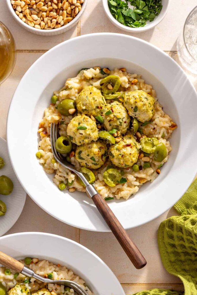 Lemon artichoke meatballs over creamy parmesan rice topped with pine nuts, herbs and red pepper flakes