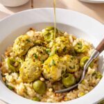 Lemon artichoke chicken meatballs served over creamy parmesan rice with Castelvetrano olives and olive oil drizzled on top