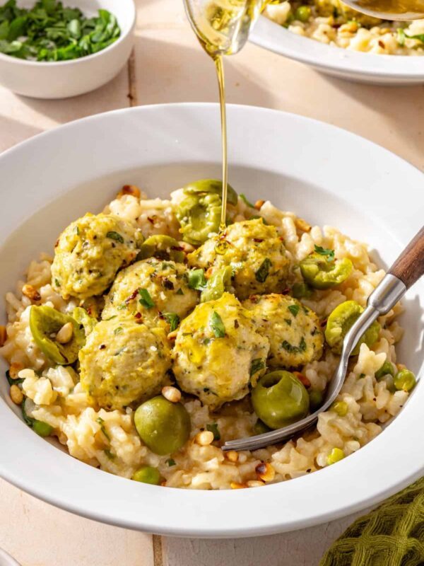 Lemon artichoke chicken meatballs served over creamy parmesan rice with Castelvetrano olives and olive oil drizzled on top