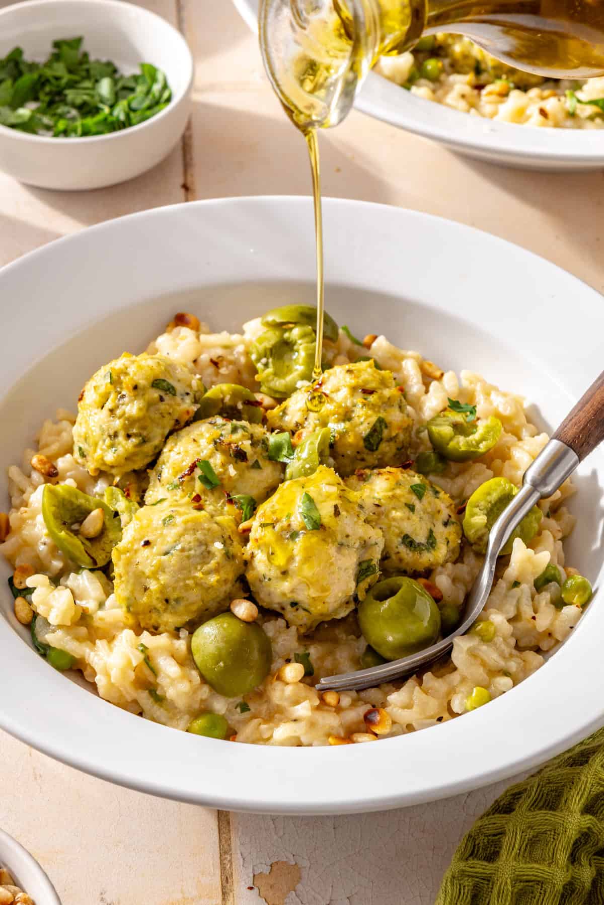 Lemon artichoke chicken meatballs served over creamy parmesan rice with Castelvetrano olives and olive oil drizzled on top