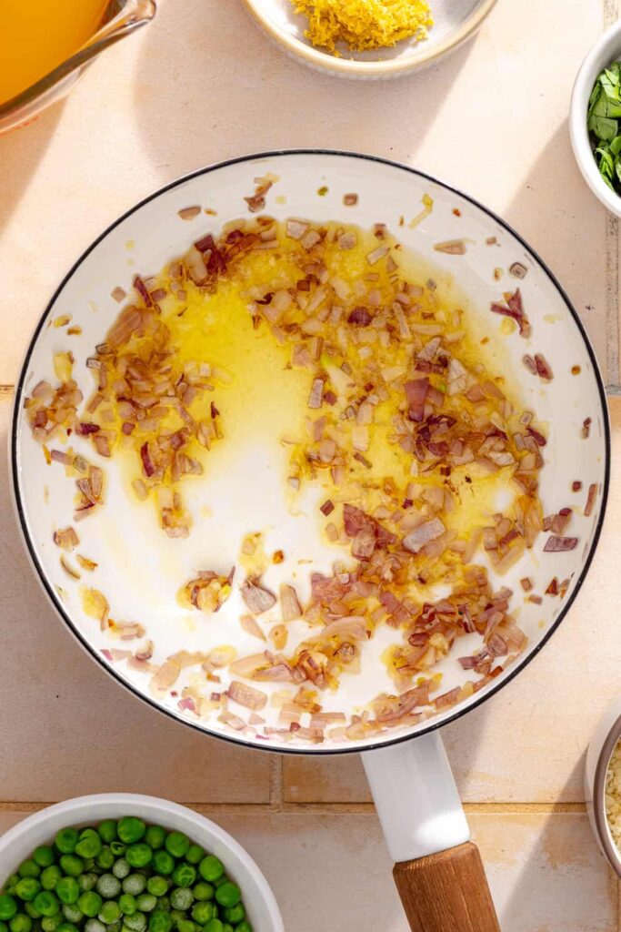 Shallot sautéing in a skillet for creamy parmesan rice