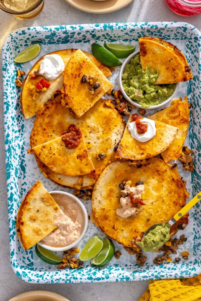 Crispy quesadilla wedges served with extra street corn filling, guacamole and lime