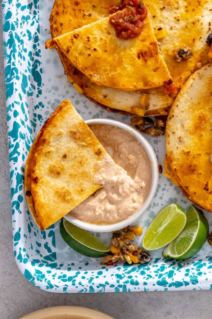 Sheet pan quesadilla wedge dipped into leftover street corn sauce with lime