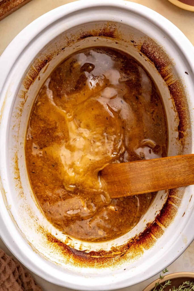 Apple cider gravy stirred in the slow cooker as the arrowroot slurry thickens the sauce.