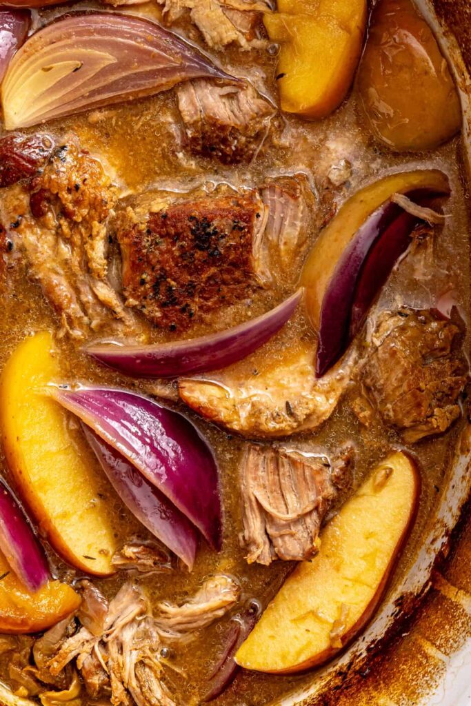 Tender apple cider pork with juicy shredded meat, thick cider gravy, and a caramelized apple wedge.