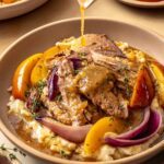 Slow cooker apple cider pork served over mashed potatoes with fresh thyme as cider gravy is poured over the top.