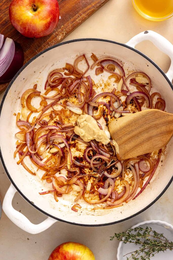Dijon mustard added to the garlic and red onion mixture sautéing together in a skillet for slow cooker pork.
