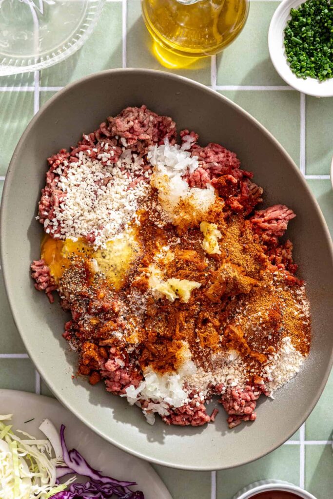 Ground beef mixed with breadcrumbs, egg, grated onion, garlic, smoked paprika, chili powder, and seasonings for BBQ meatballs.