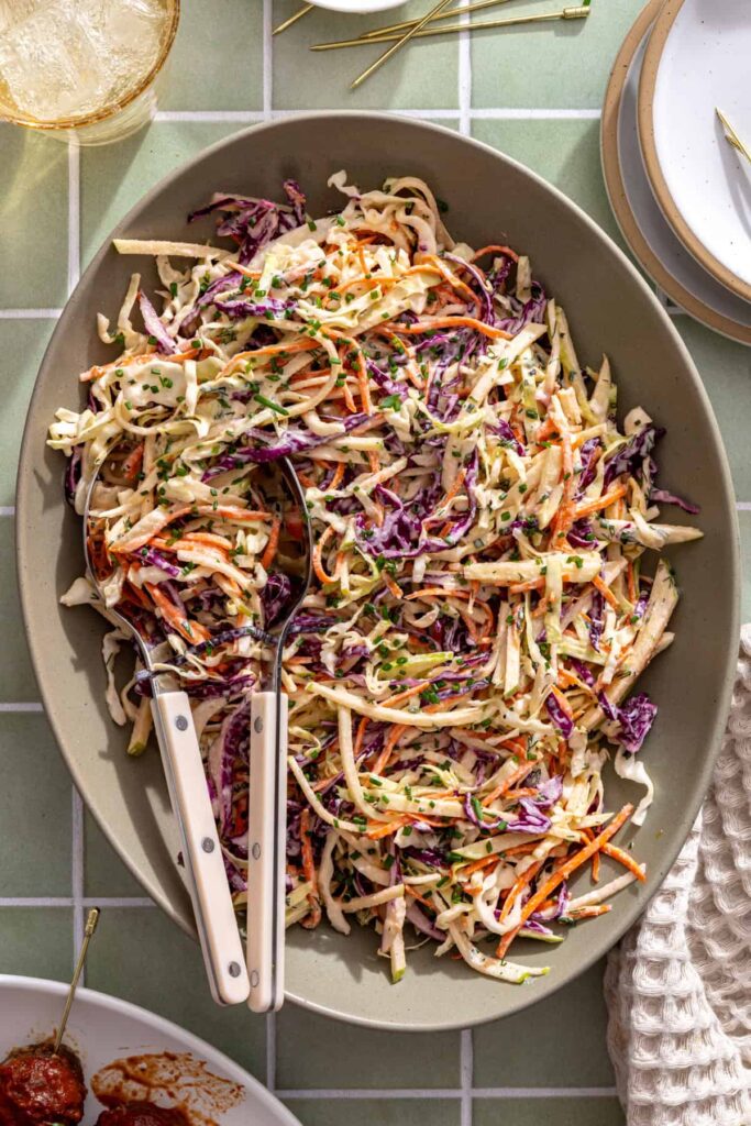 Overhead view of creamy Greek yogurt ranch slaw with green and red cabbage, carrots, and green apple in a serving platter.