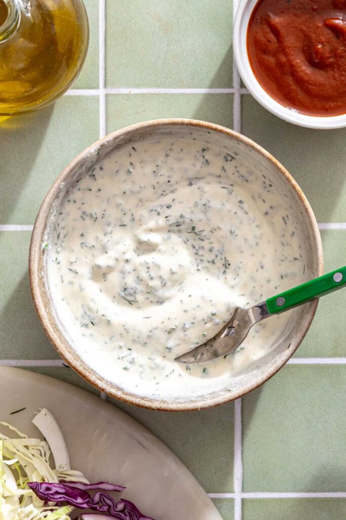 Whisking Greek yogurt, olive oil, lemon juice, Dijon mustard, garlic powder, onion powder, dill, and chives to make homemade ranch dressing.