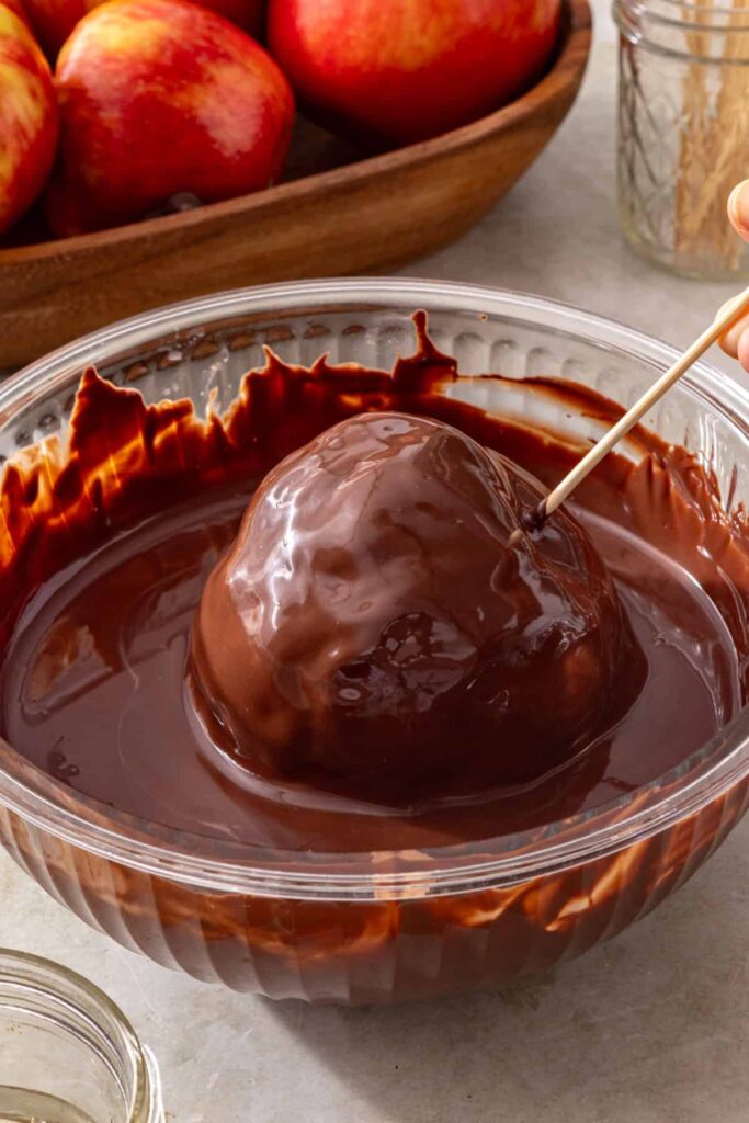 Honeycrisp apple being covered in melted dark chocolate